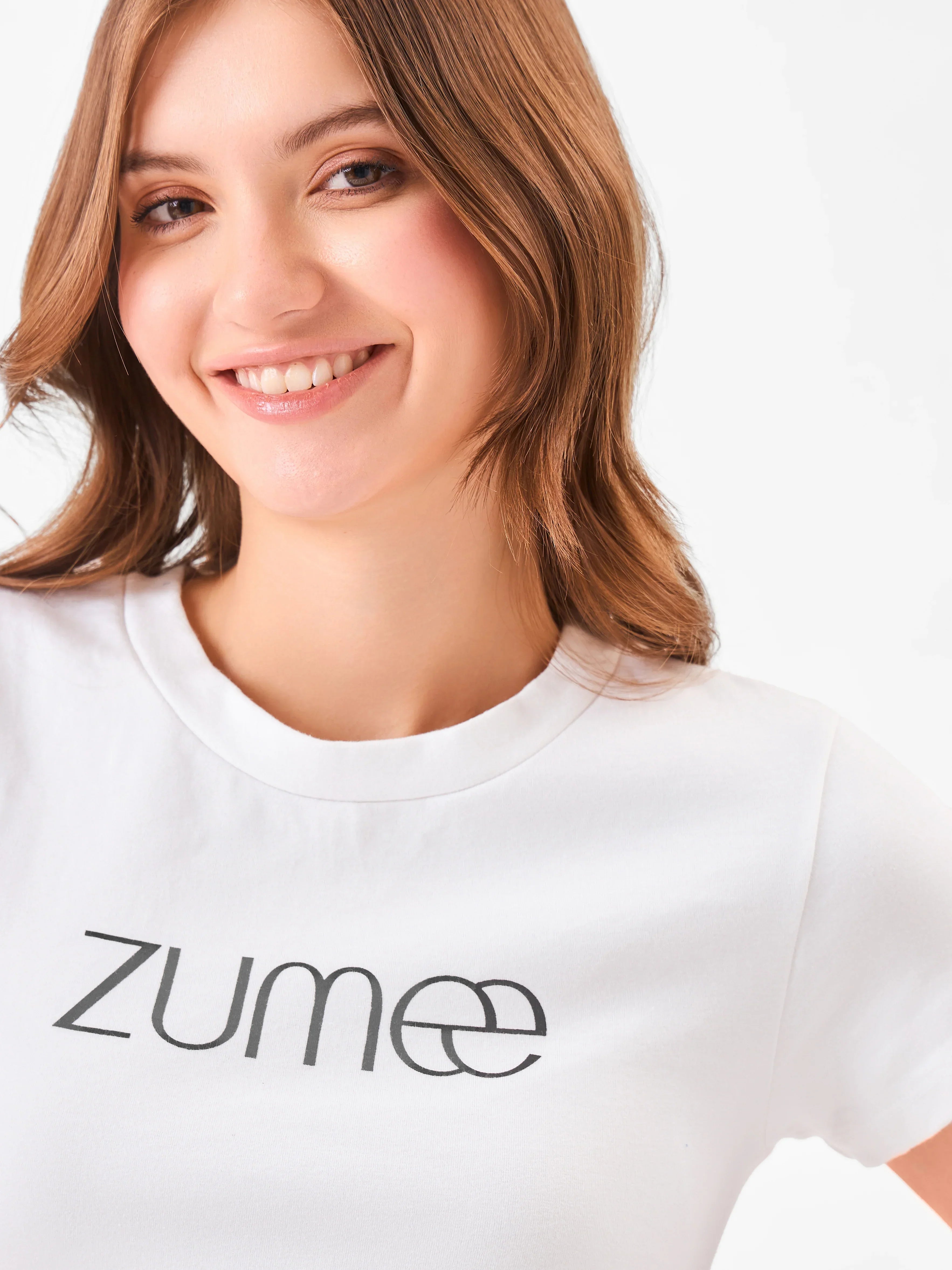 Female model wearing a round neck white t-shirt with 'Zume' logo from Stylera
