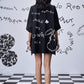 Back view of model wearing Stylera black scribble print shirt oversized boxy fit with white doodle motif