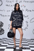 Stylera model wearing black scribble print shirt oversized hoodie style with shorts and black bag