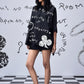 Stylera model wearing black scribble print shirt oversized tunic with white doodle clover graphic