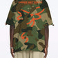Stylera camo bowling shirt back view showing green camouflage with orange graphic text and abstract logo