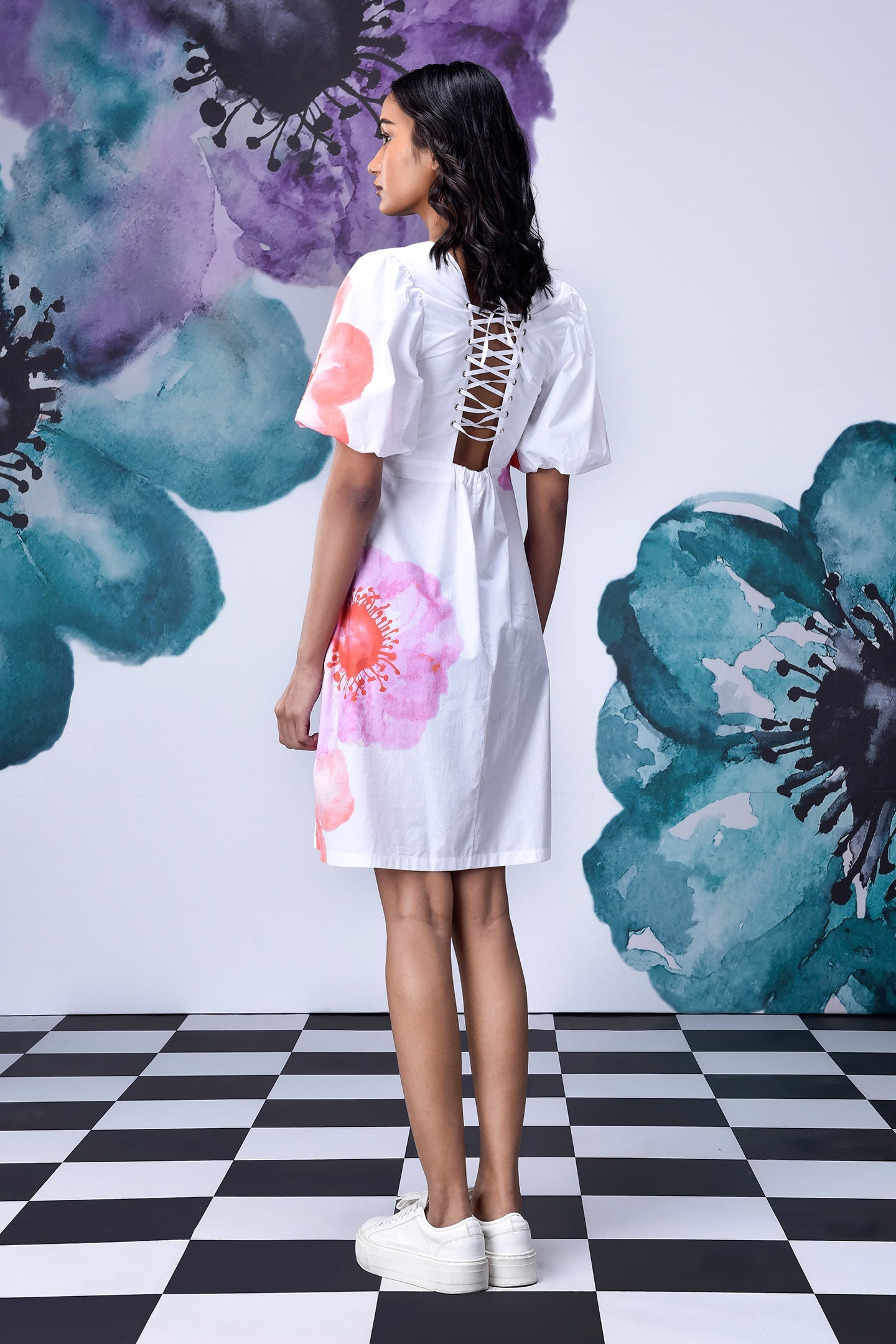 Back view of model in white lace up back casual floral dress for women with puff sleeves and platform sneakers
