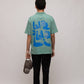 Stylera casual men's fashion polo mint green with blue back graphic worn by model holding cap and black pants