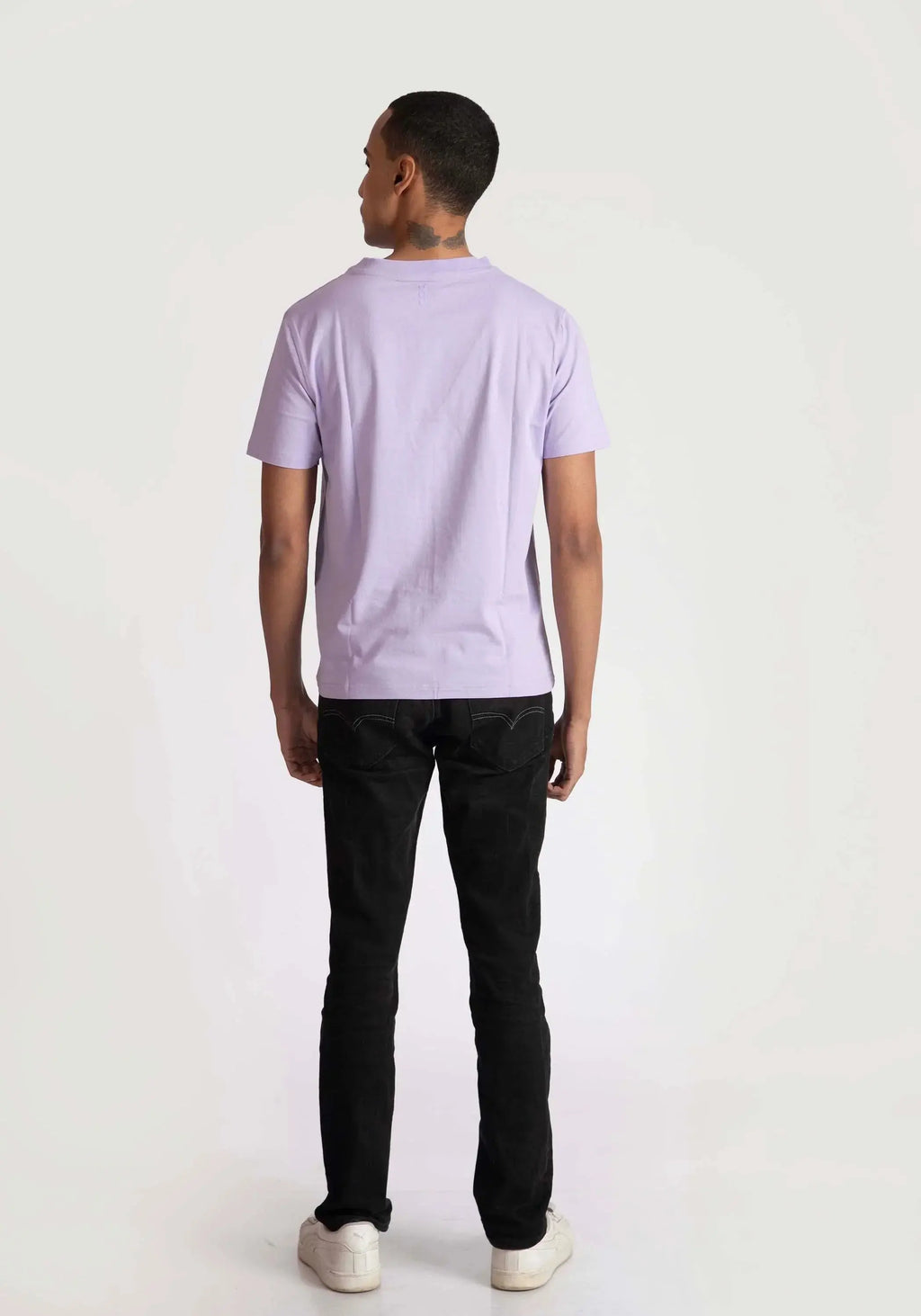Back view of a man wearing a lavender t-shirt for men paired with black pants and white shoes