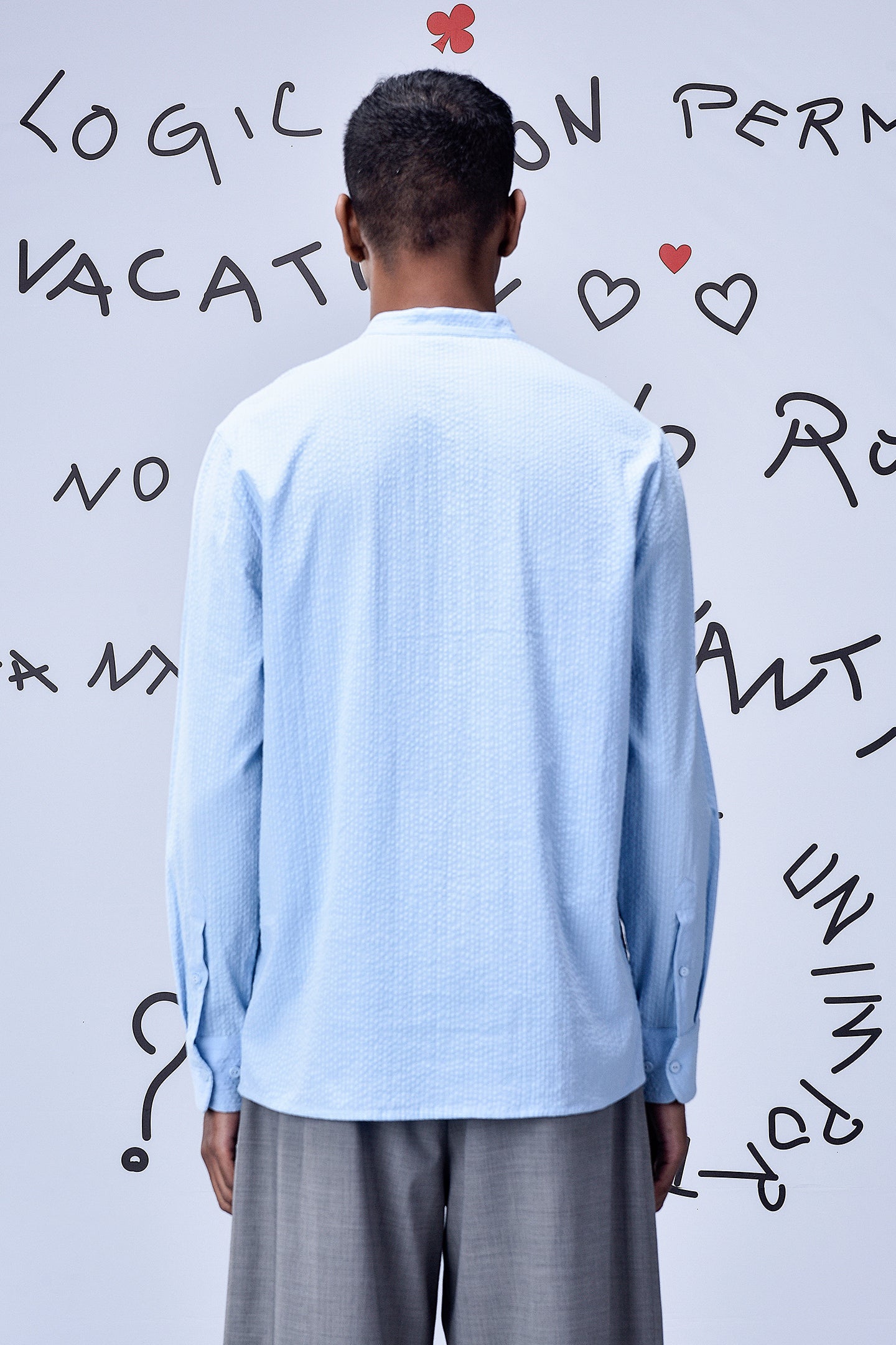 Back view of man wearing light blue regular fit shirt by Stylera paired with gray pants