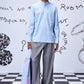 Man wearing a light blue regular fit shirt by Stylera paired with gray pants and holding a striped tote bag