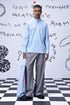 Man wearing a light blue regular fit shirt by Stylera paired with gray pants and holding a striped tote bag