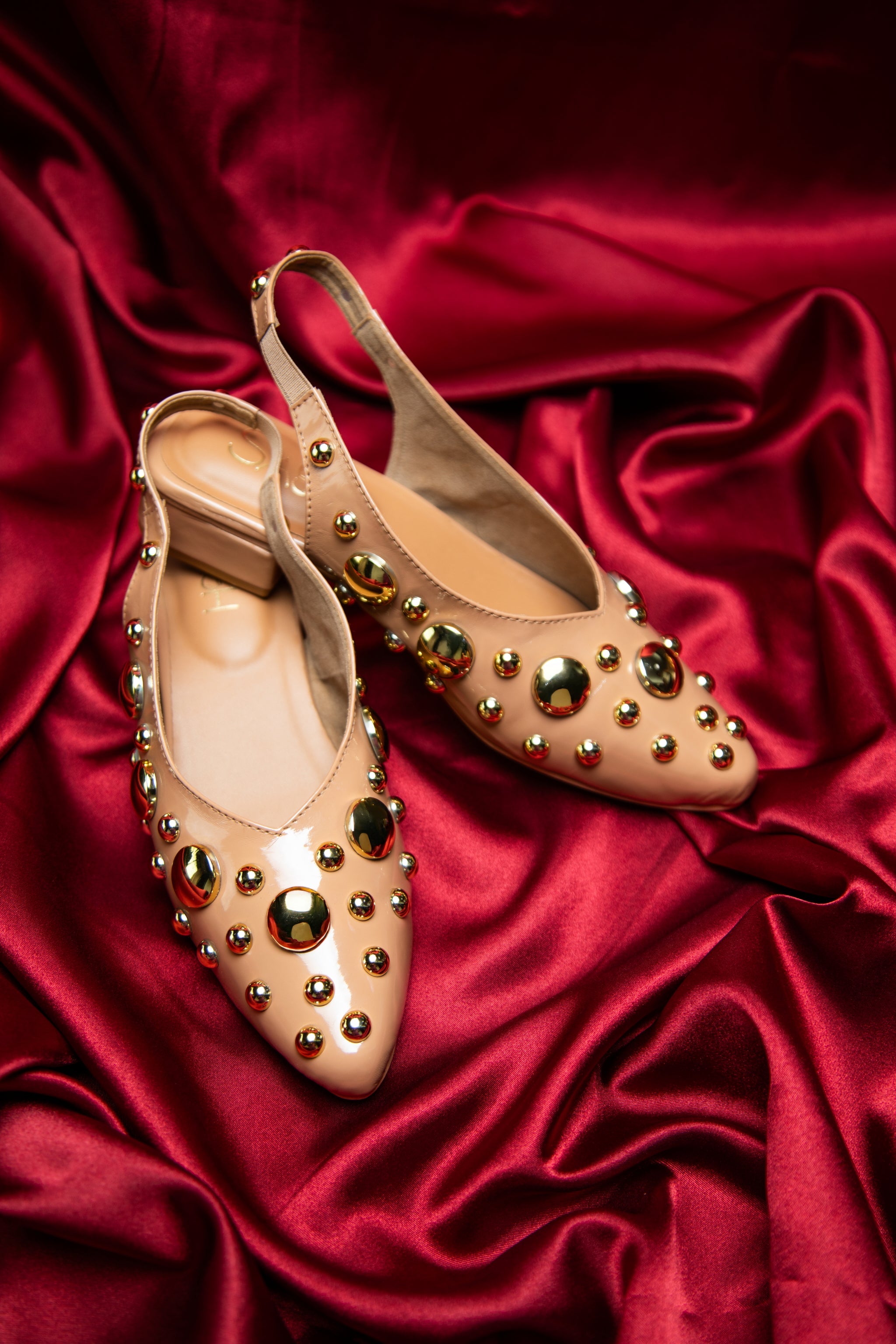 Light Gold studded flats heels by Stylera with decorative round studs on satin background
