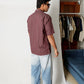 Rear view of model wearing Stylera men's maroon striped shirt with light wash jeans in studio