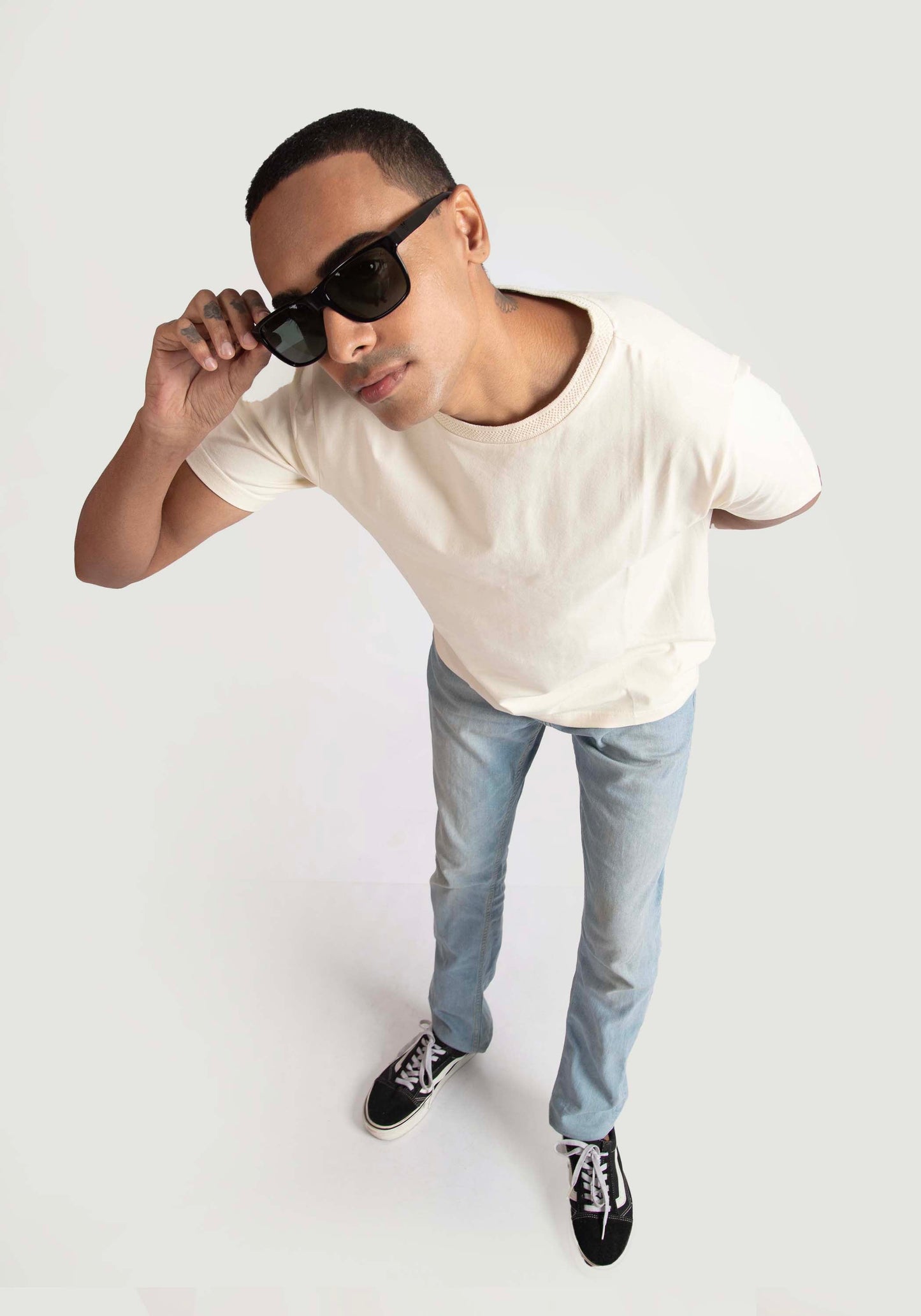 Man wearing Stylera men's trendy cream t-shirt paired with light blue jeans and black sneakers