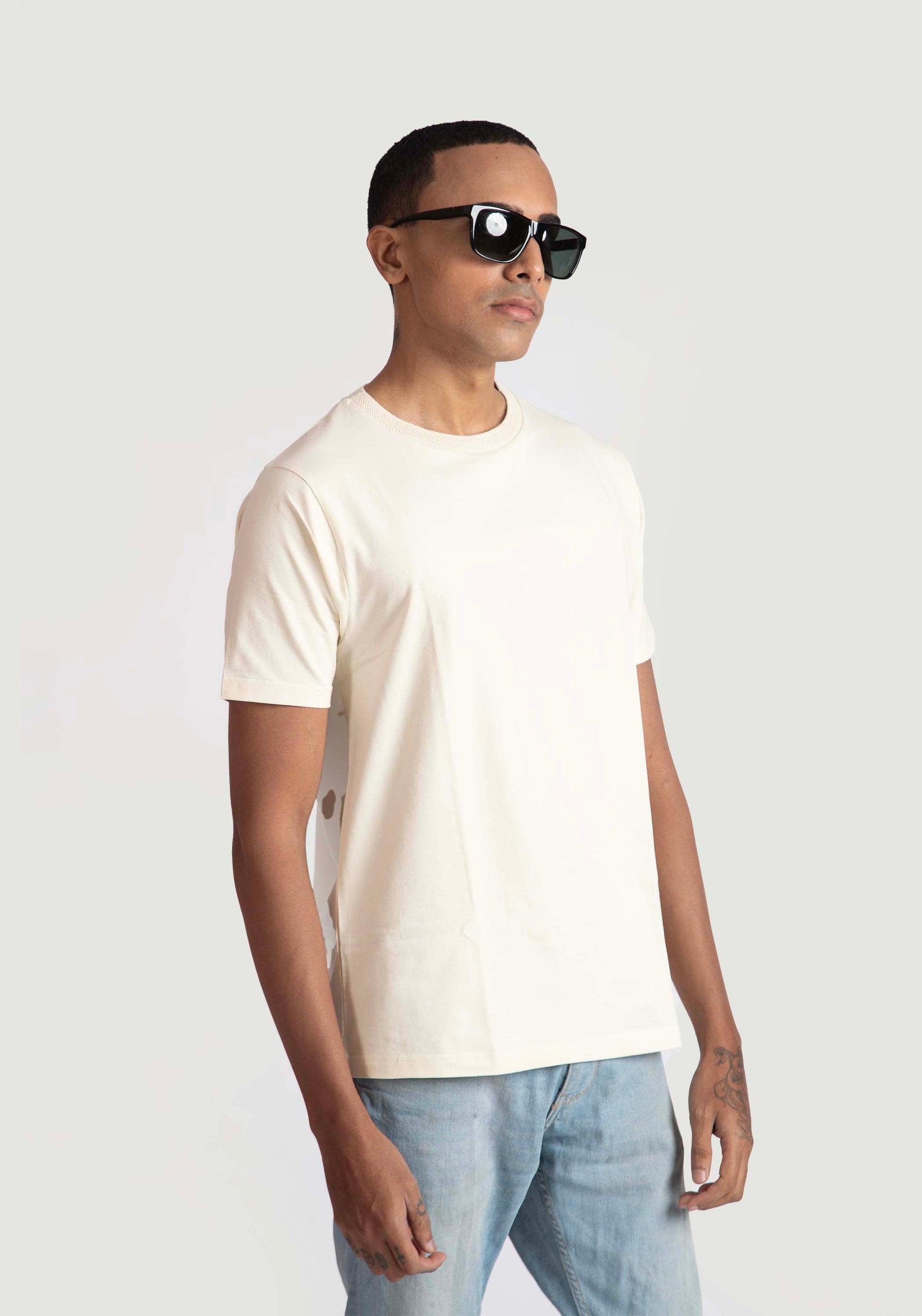 Stylera men's trendy cream t-shirt worn by model with sunglasses and light blue jeans