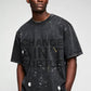 Stylera washed black oversized men's trendy graphic tee with bold text print and paint splatter detail on model