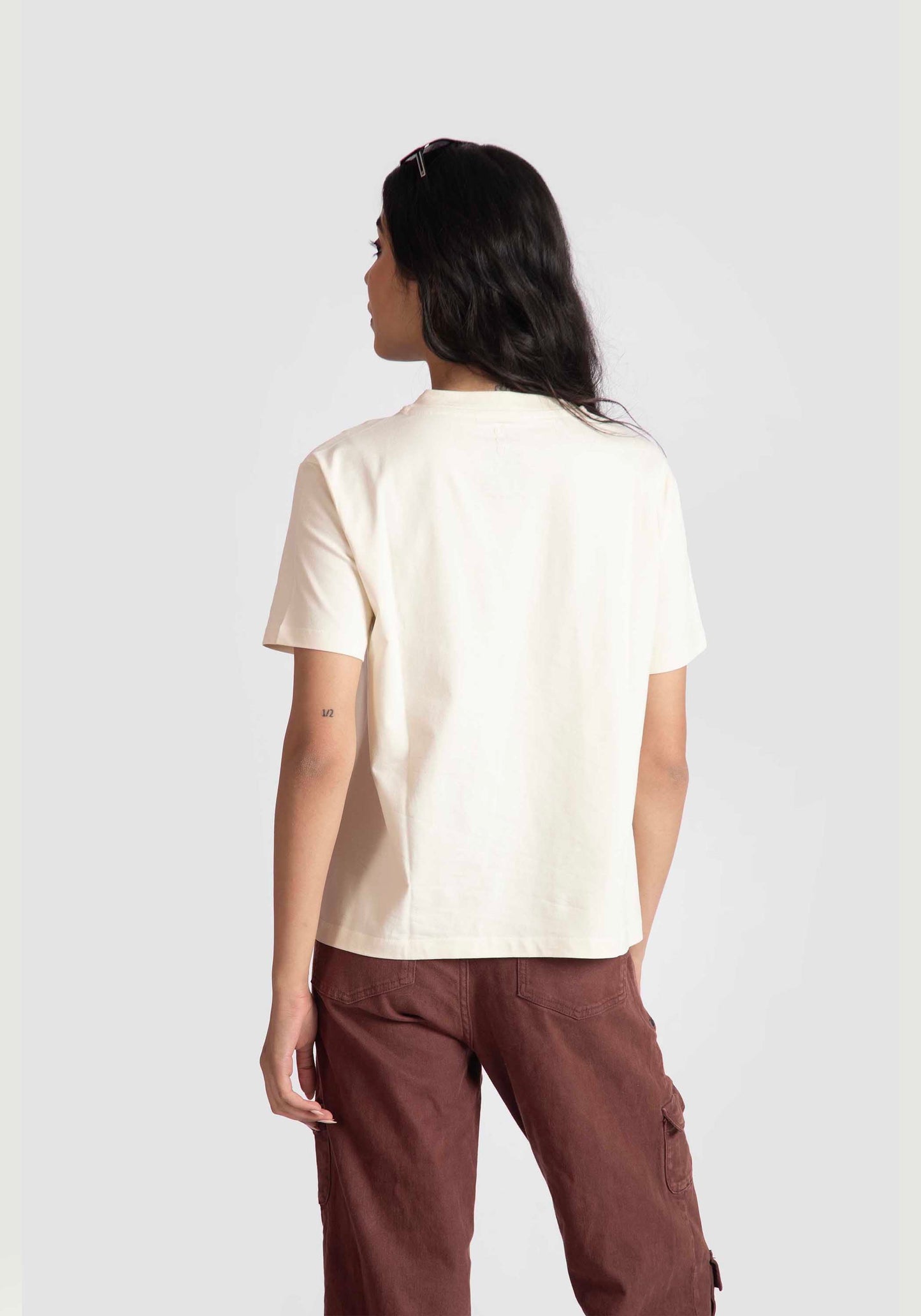 Back view of woman wearing motivational quote off white t-shirt for women paired with brown pants