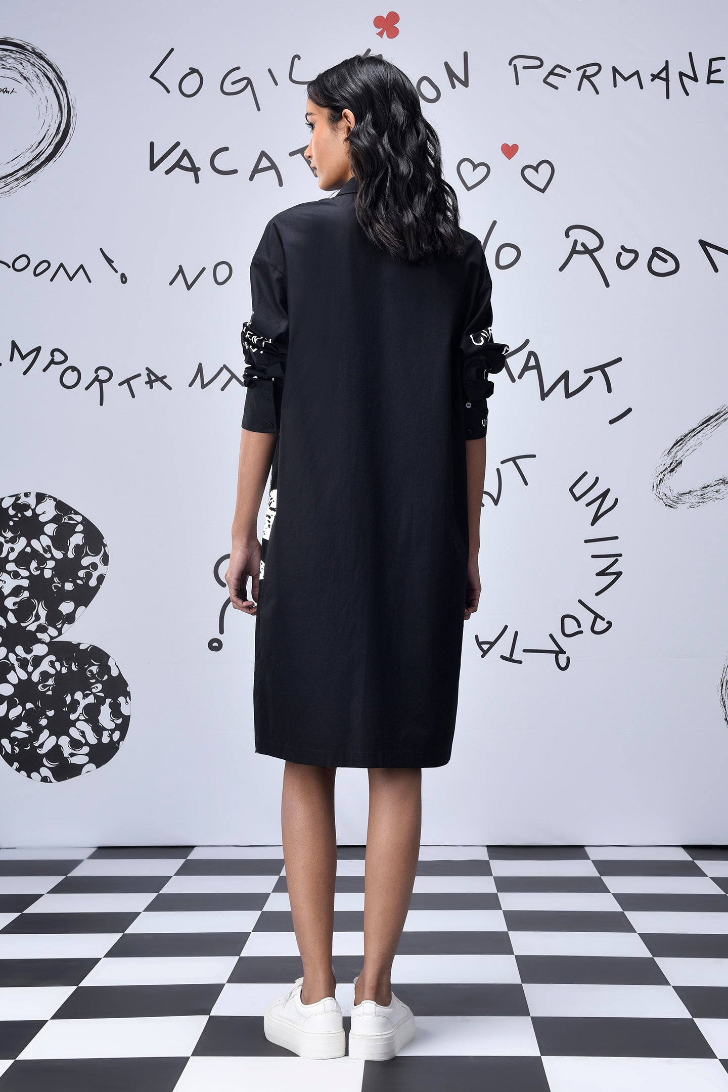 Back view of Stylera oversized black shirt dress trendy knee length with sequin sleeve detail and white sneakers