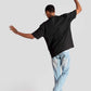 Back view of man wearing oversized fashion t-shirt for men in black with light blue jeans
