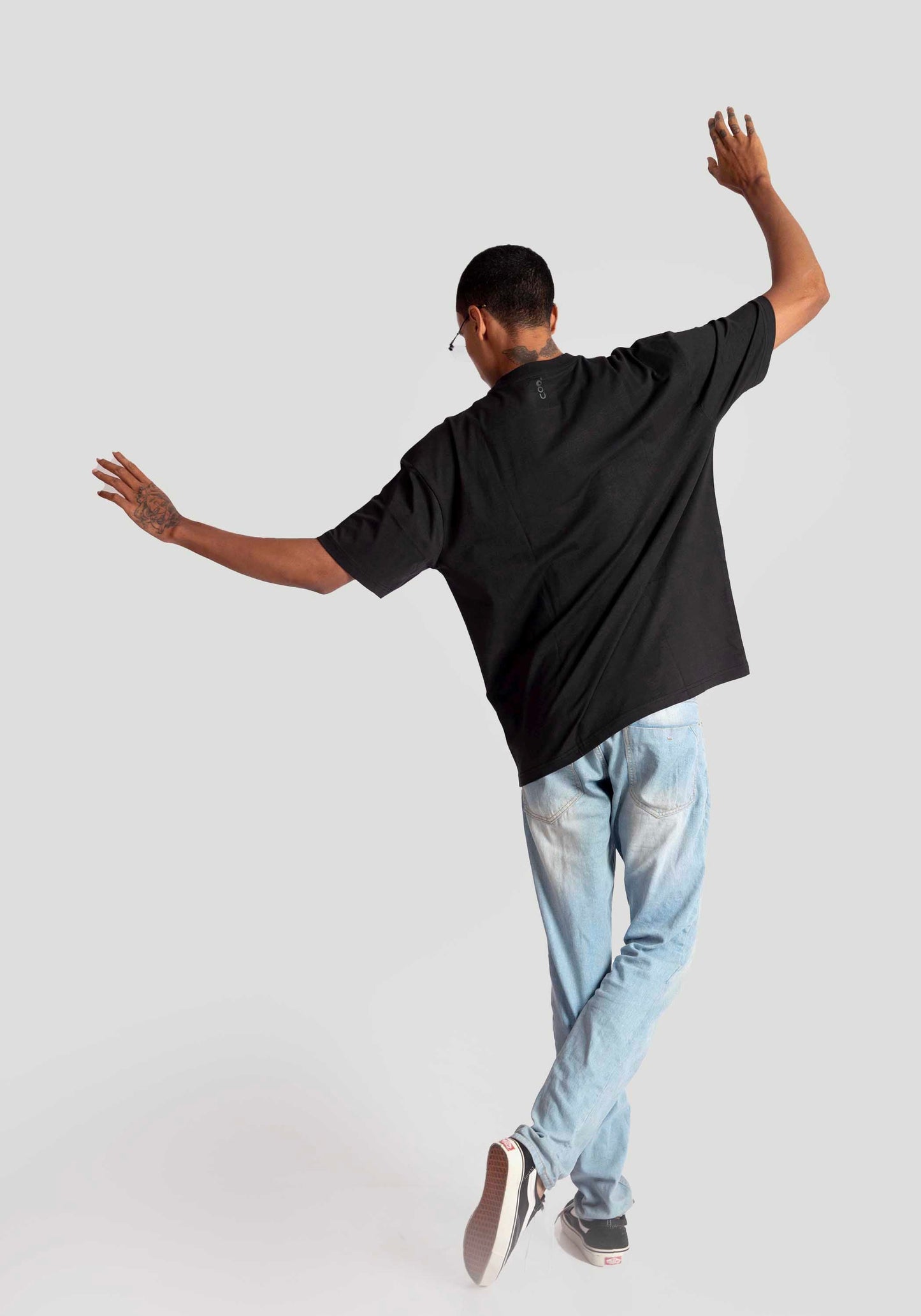 Back view of man wearing oversized fashion t-shirt for men in black with light blue jeans