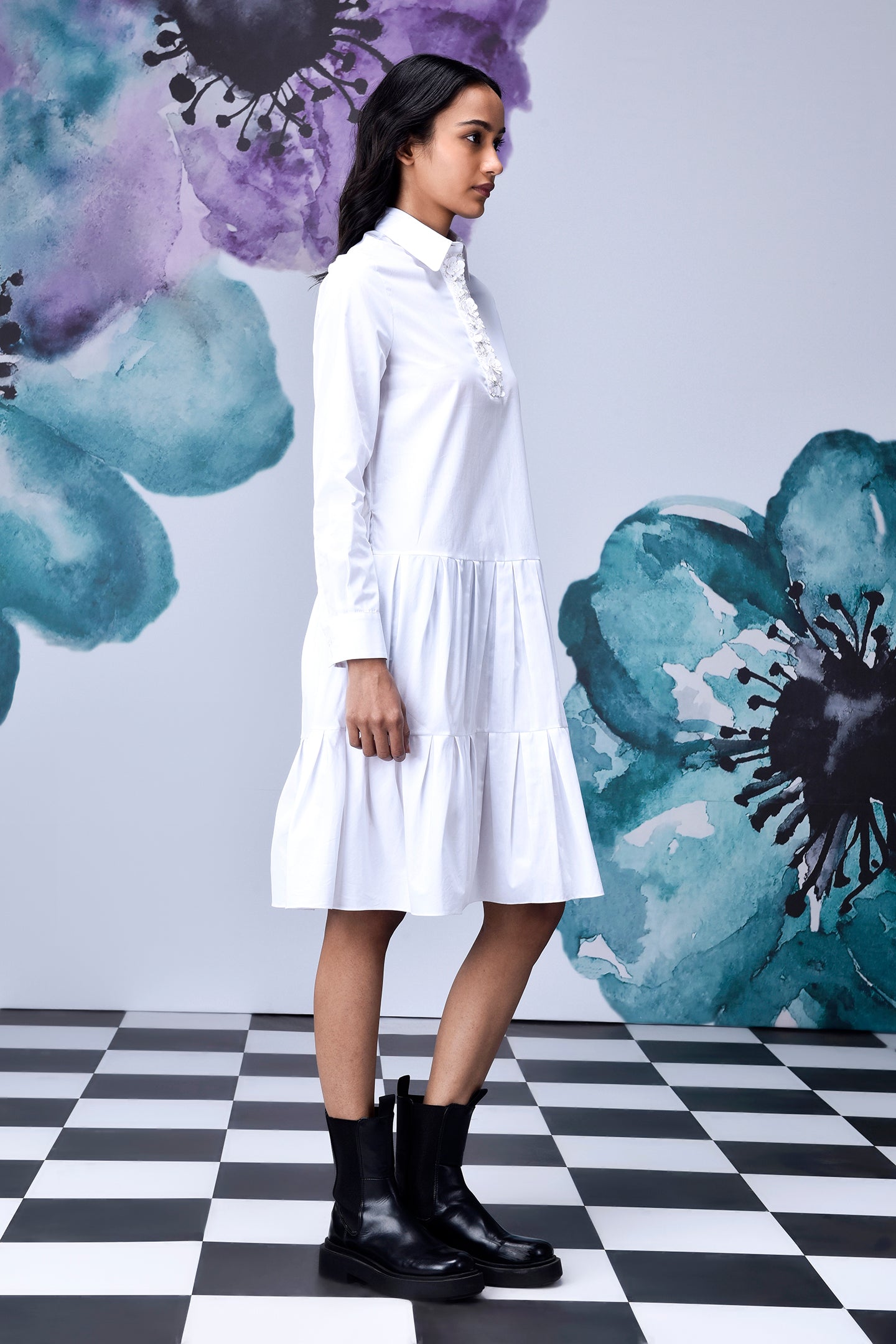 Stylera model wearing relaxed fit white dress for women with tiered skirt and black boots