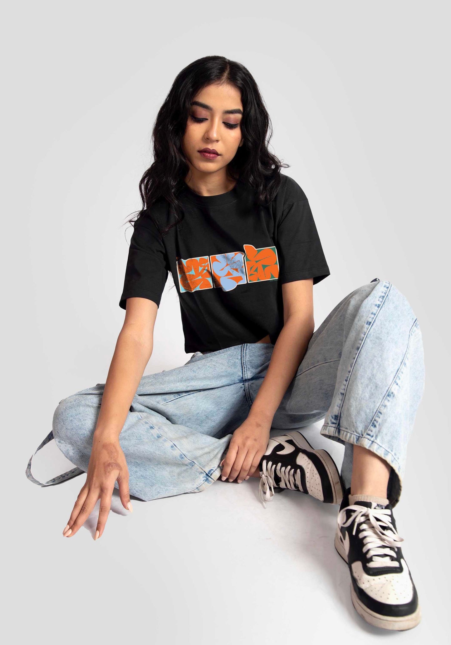 Stylera trendy black oversized crop fit t-shirt worn by model with light blue jeans and sneakers