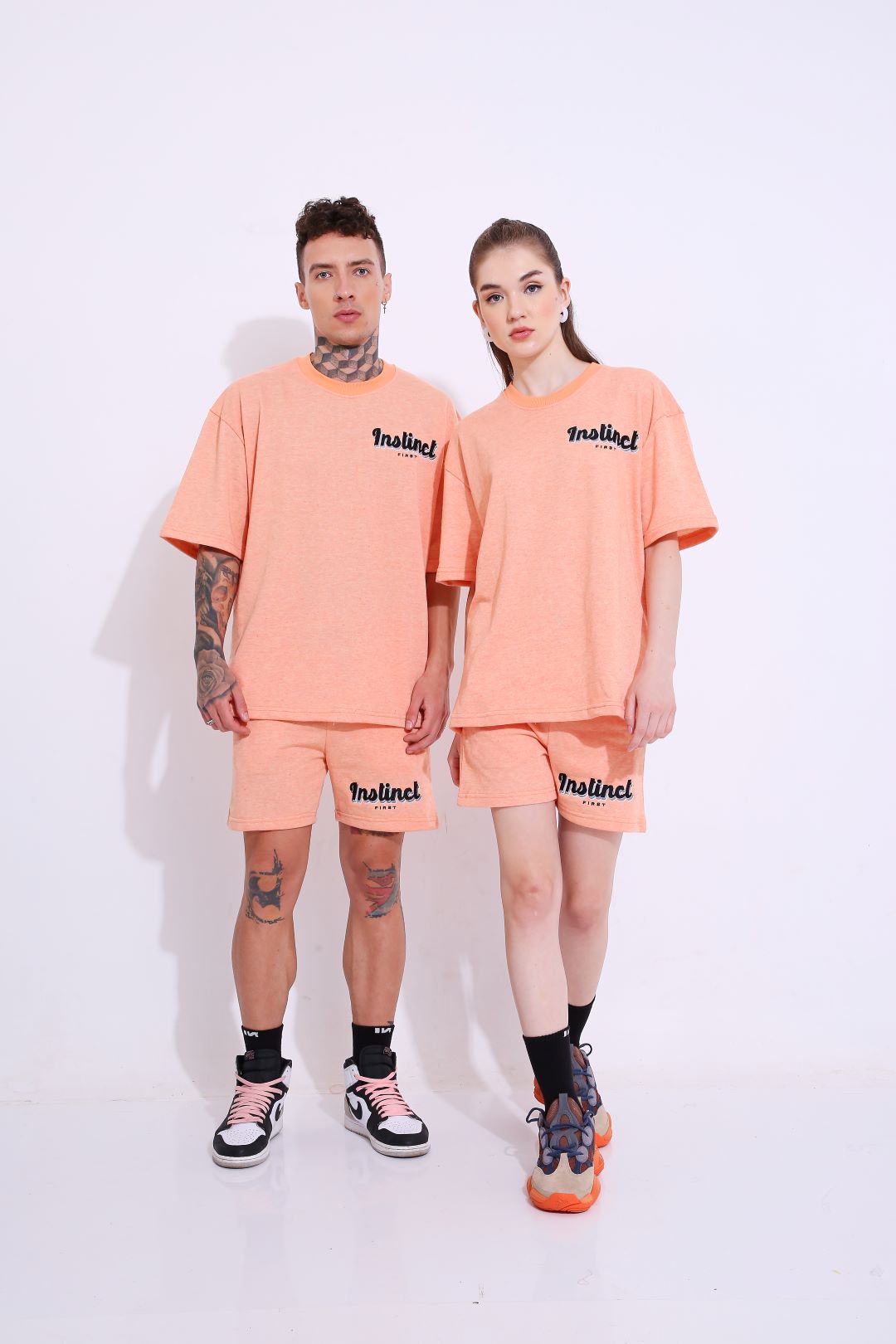 Male and female models wearing Stylera peach matching set with trendy oversized casual t-shirt and shorts