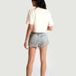 Woman wearing Stylera white oversized crop fit tee with light denim shorts and sneakers standing facing away