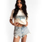 Woman wearing a white oversized crop fit tee with graphic print and distressed denim shorts