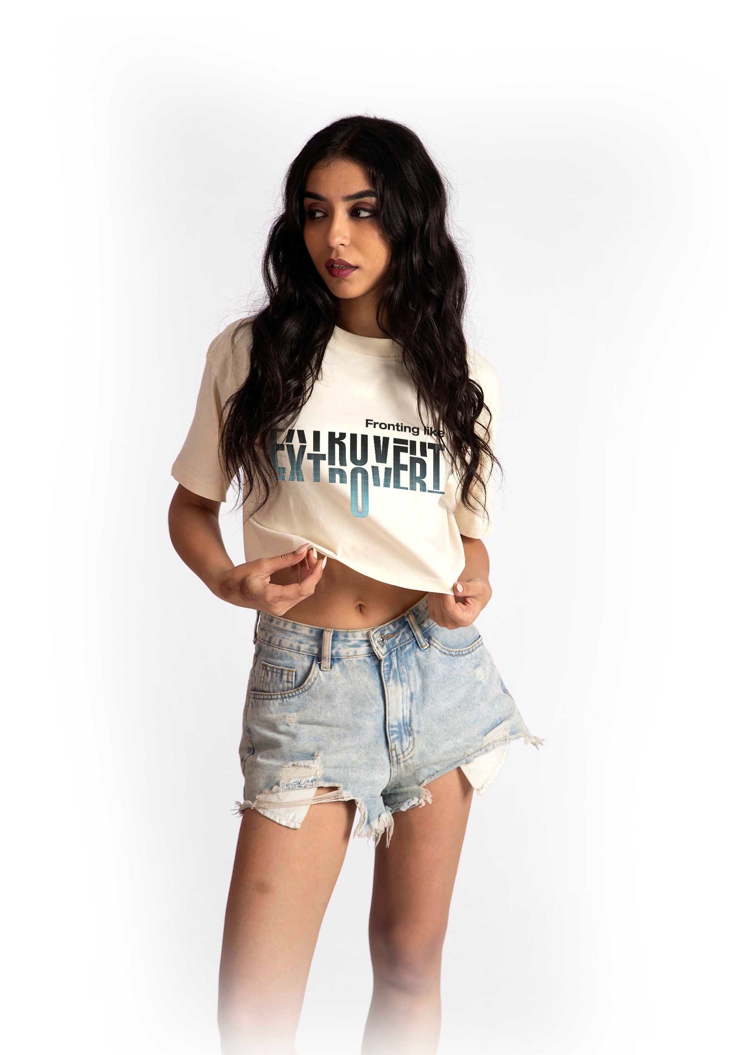 Woman wearing a white oversized crop fit tee with graphic print and distressed denim shorts