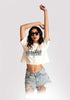 Woman wearing Stylera white oversized crop fit tee with graphic print and denim shorts