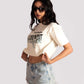 Woman wearing white oversized crop fit tee with graphic text and denim shorts by Stylera
