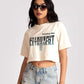 Woman wearing white oversized crop fit tee with graphic text paired with distressed denim shorts