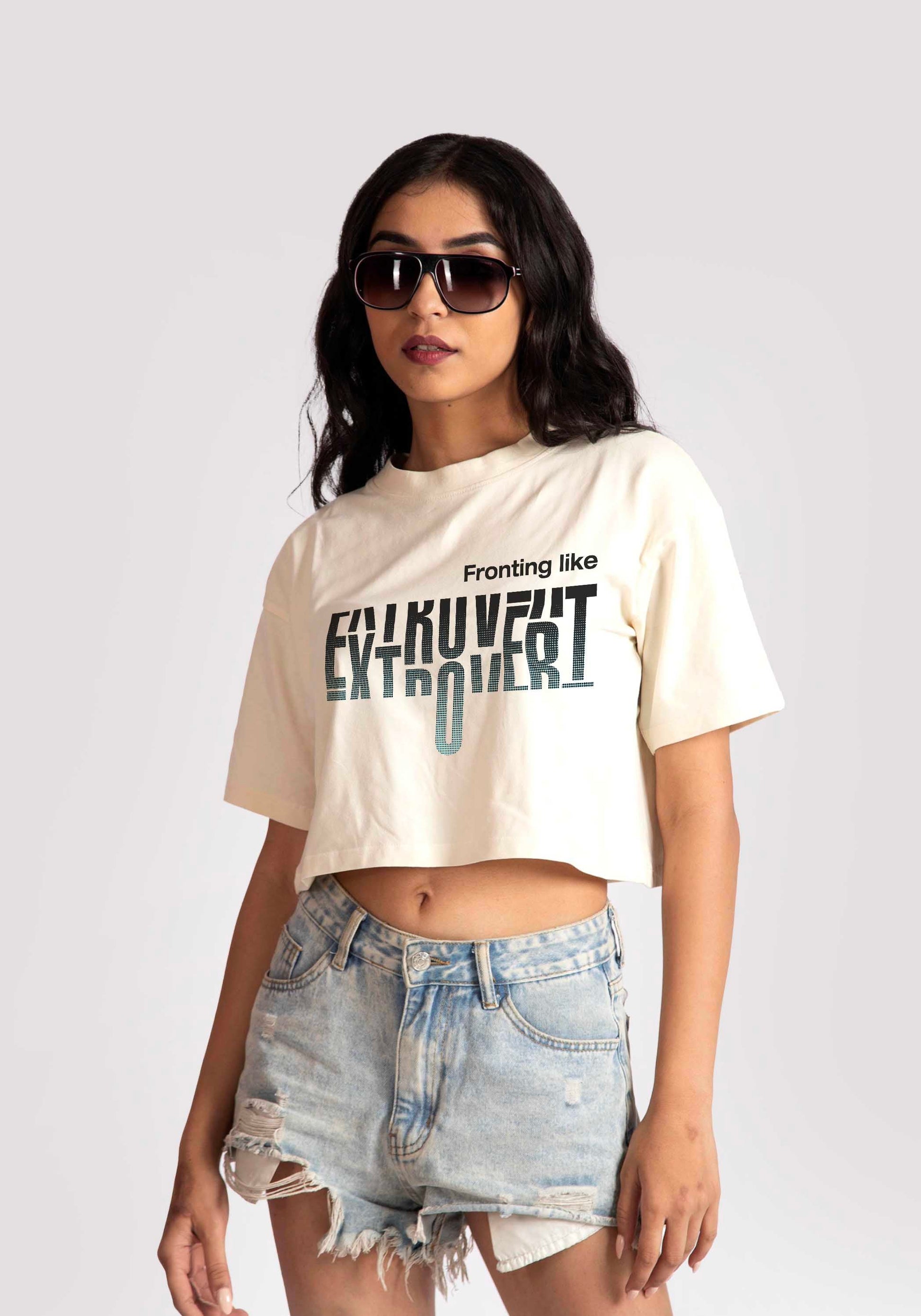 Woman wearing white oversized crop fit tee with graphic text paired with distressed denim shorts