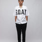 Stylera model wearing white trendy summer shirt with bold GOAT chest print short sleeves black pants