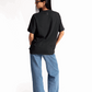 Back view of a woman wearing Stylera women's relaxed fit black tee paired with blue jeans and white sneakers