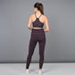 A woman wearing Wine Leggings stands facing away with her hands behind her back, set against a plain gray background.