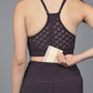 Wearing the Wine Netted Top, a woman in workout clothes slips a small wallet into the back waistband pocket of her leggings.