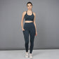 A woman models the Teal Netted Top with blue leggings, standing with one hand in her pocket against a gray background.