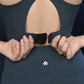 Person fastening a Teal Netted Top at the back, paired with navy blue activewear.