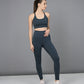 A woman models the Teal Netted Top with matching honeycomb-patterned leggings, standing against a gray background and looking to the side.