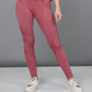 Model showcases Peony Pink Leggings featuring mesh panels, paired with white sneakers, standing against a plain gray background.