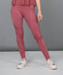 Model showcases Peony Pink Leggings featuring mesh panels, paired with white sneakers, standing against a plain gray background.