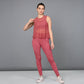 A woman models Peony Pink Leggings with a pink mesh tank top, posing gracefully against a plain gray background.