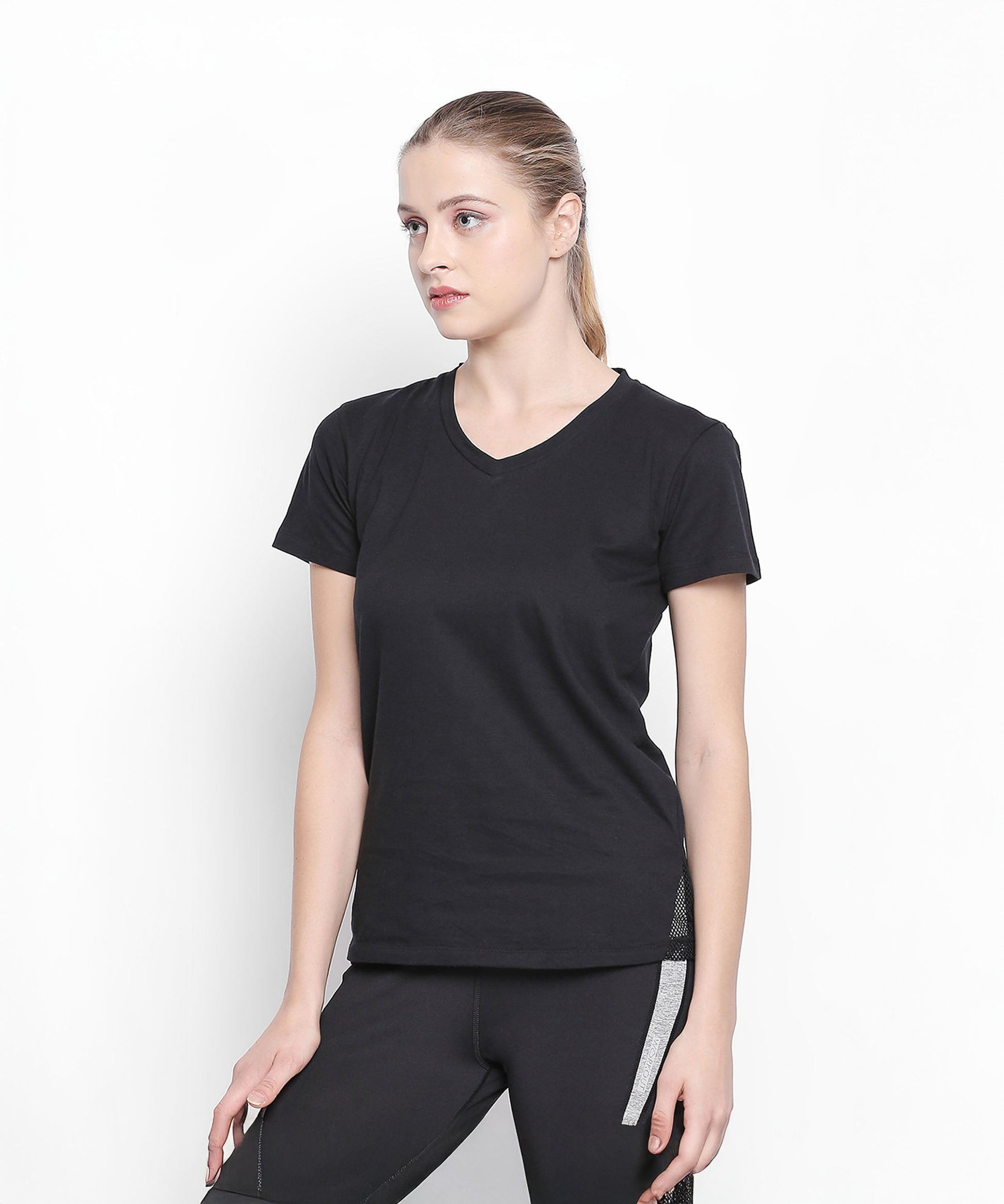Woman in a Tuna London Sara Basic Sports Tee with net detailing, paired with black pants, standing against a plain white background.