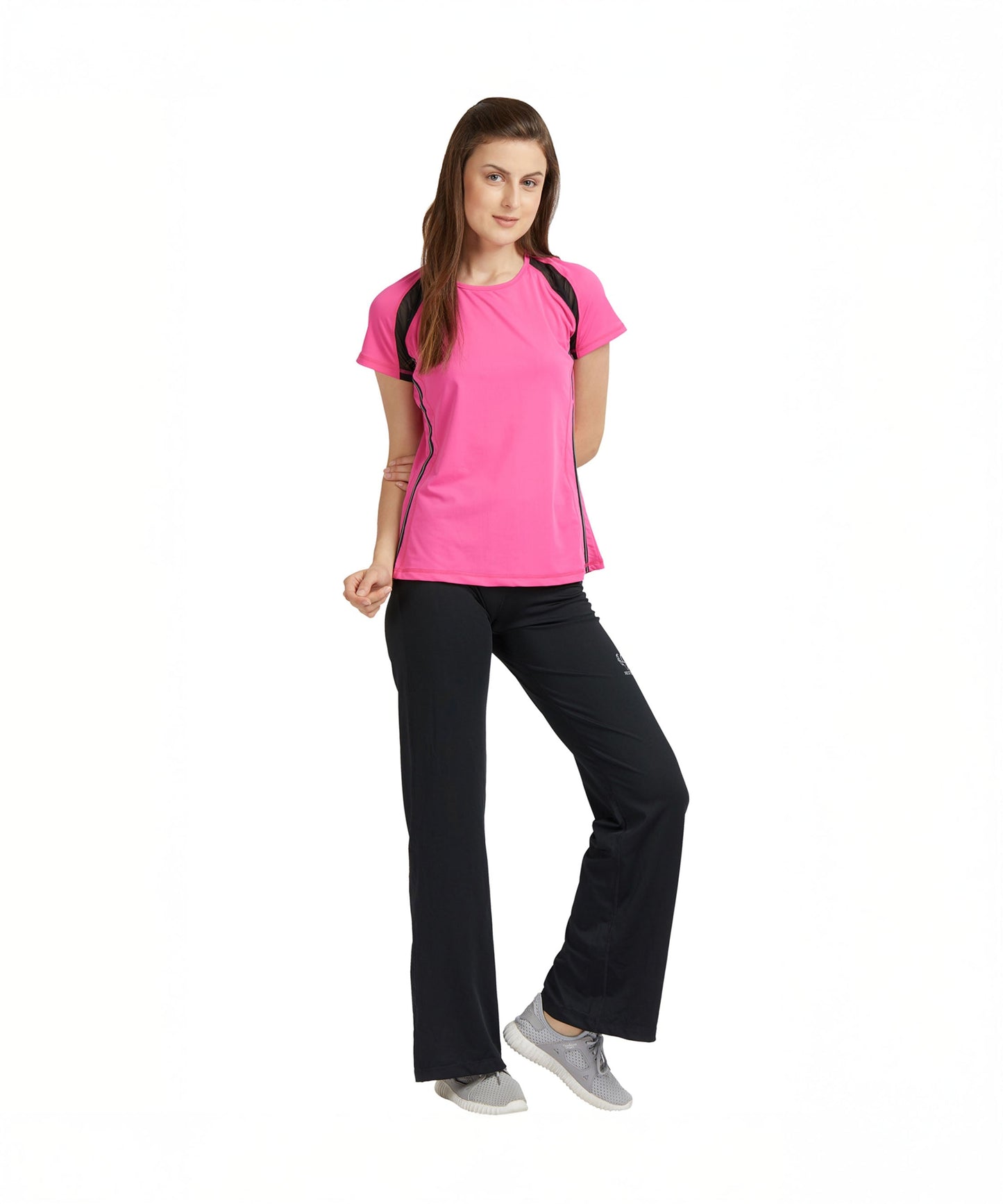 A woman poses confidently against a white background, wearing the Tuna London Pink Poly Blend Round Neck Women’s T-Shirt and black workout pants, styled for the gym.