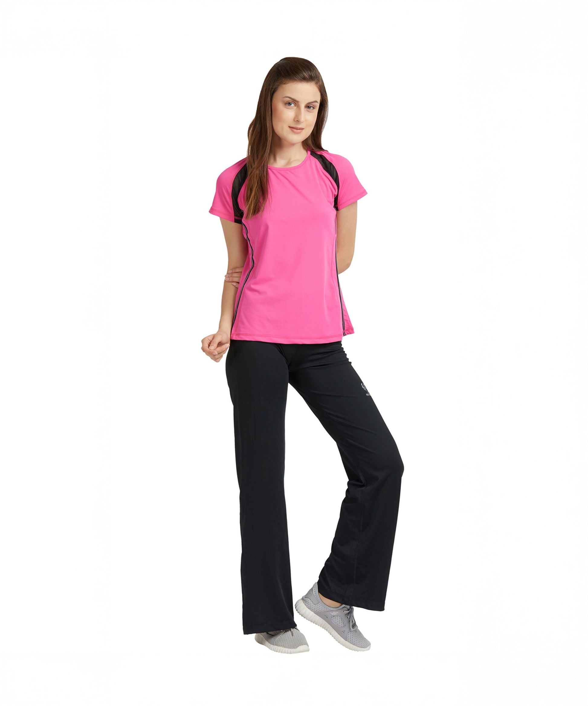 A woman poses confidently against a white background, wearing the Tuna London Pink Poly Blend Round Neck Women’s T-Shirt and black workout pants, styled for the gym.