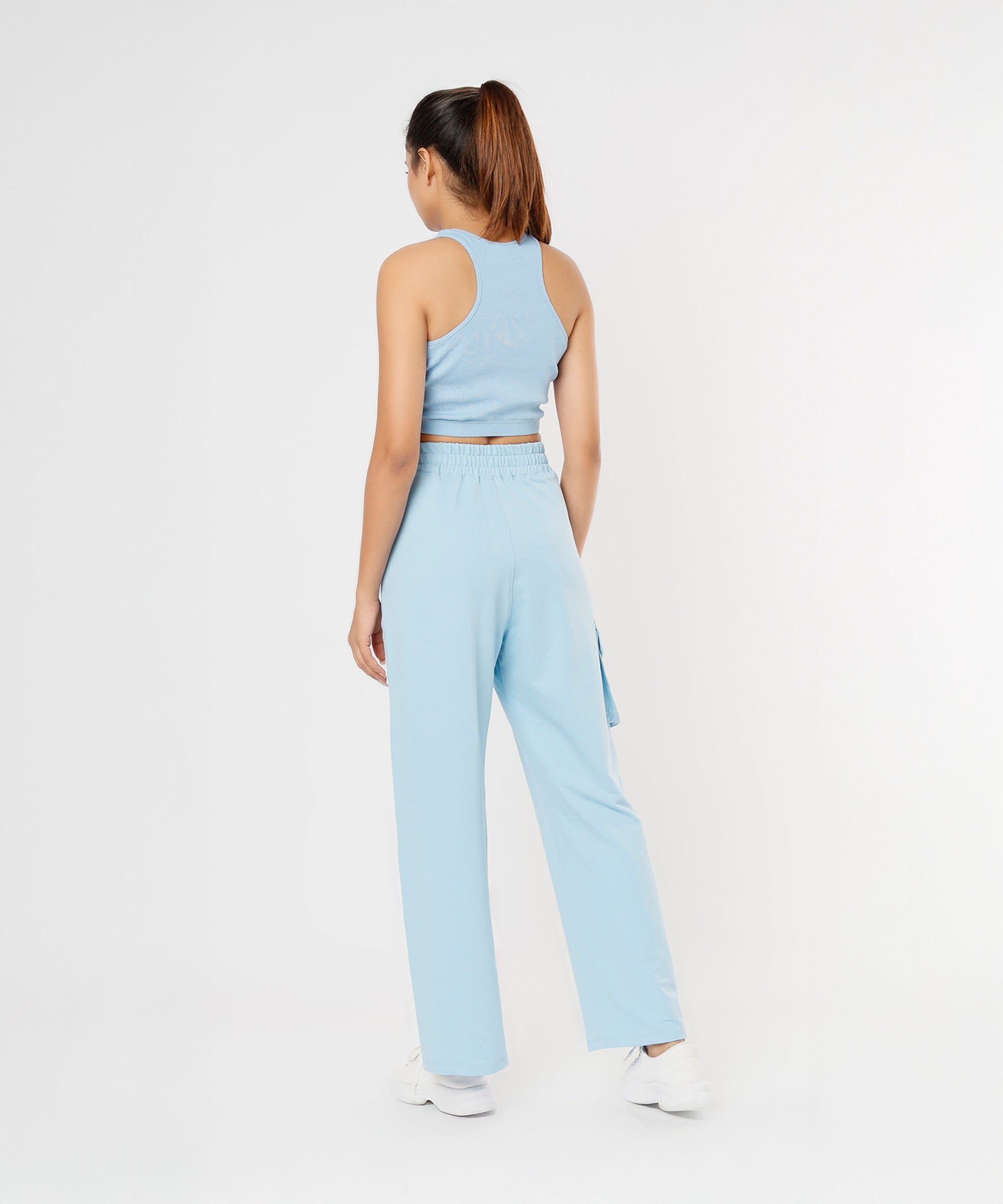 A woman models the Blossom Blue Set with Crop Top and matching pants, standing with her back to the camera in a white studio.