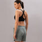 A woman wearing the Black Sports Bra with adjustable straps and gray shorts stands sideways, looking over her shoulder.