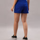 Person wearing Blue Premium Stretch Shorts With Lining and black shoes stands on a gray background, facing away from the camera.