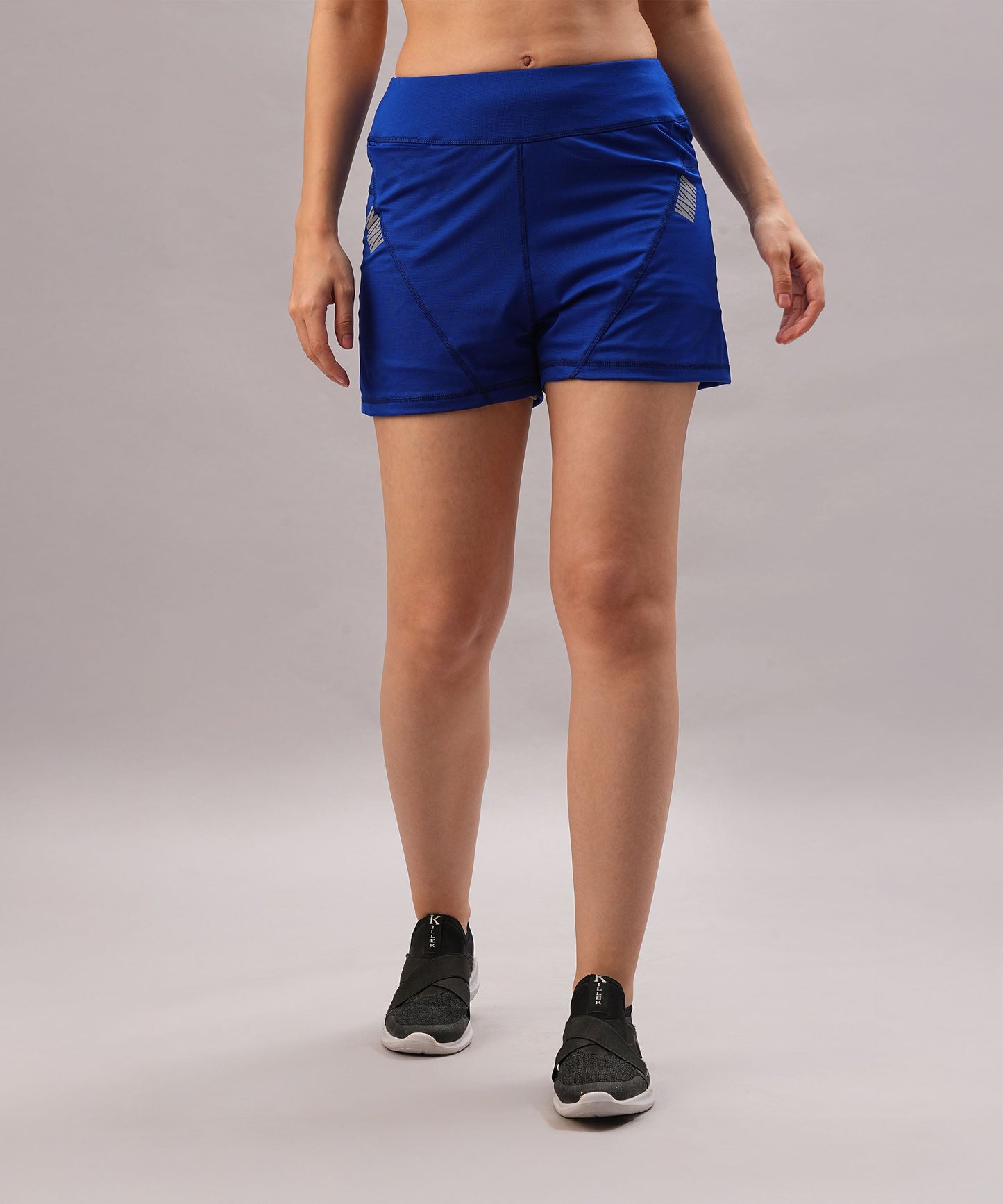 Someone stands against a plain light background wearing Blue Premium Stretch Shorts With Lining, which have a relaxed fit, paired with black sneakers.