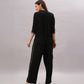 A woman faces backward against a plain light background, wearing the Black Rayon Co-Ord Set featuring a stylish top and loose-fitting pants, paired with white sneakers.