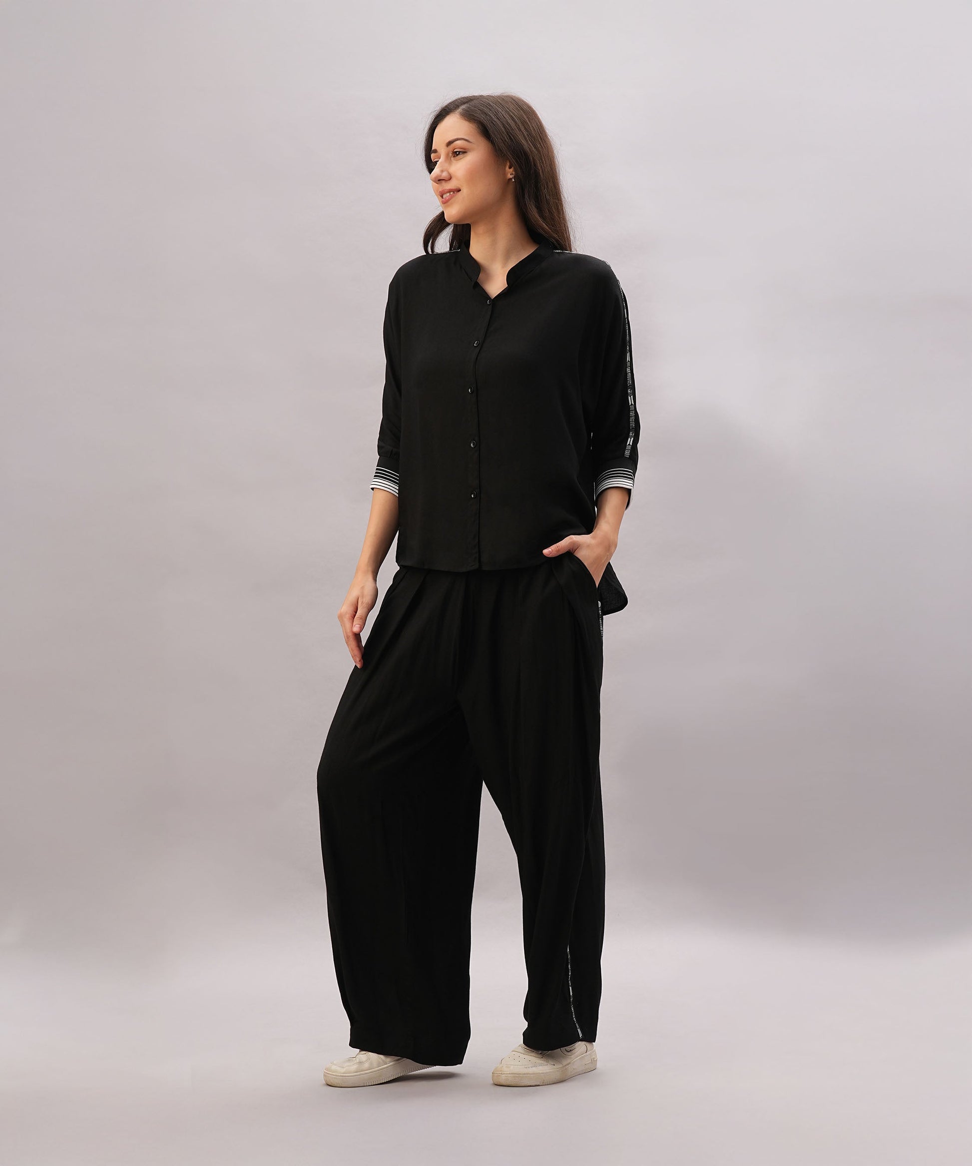 A woman models the Black Rayon Co-Ord Set, featuring a loose button-up shirt and relaxed-fit pants, against a light gray background.