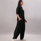 Woman wearing the Black Rayon Co-Ord Set, featuring a trendy top and wide-leg pants with side stripes, styled with white sneakers, standing sideways against a plain background.